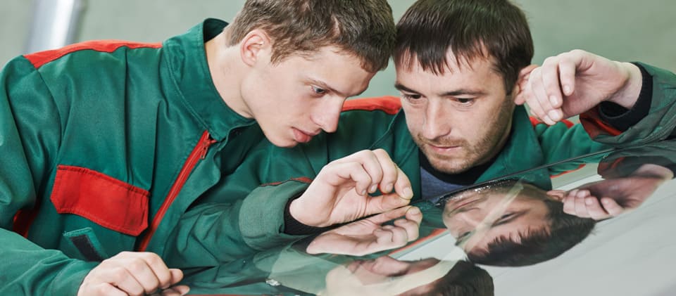 Industriemeister und Auszubildender beim Prüfen von Glas