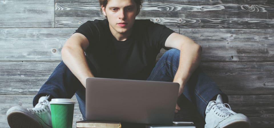 Junge schreibt am Laptop eine Onlinebewerbung für die Glasindustrie