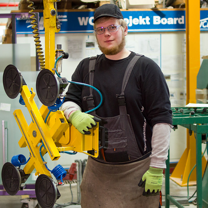 Flachglasmechaniker bedient eine Glasbearbeitungsmaschine