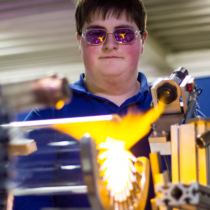 Auszubildendeer zum Verfahrensmechaniker Glastechnik bedient Maschine zur Glasbearbeitung