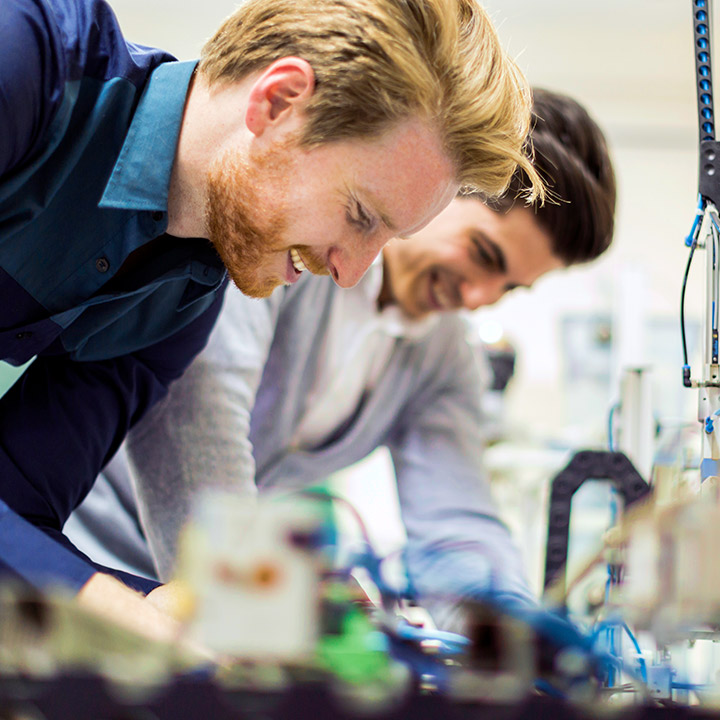 Zwei Werkstudenten tüfteln an einer Maschine für die Glasproduktion